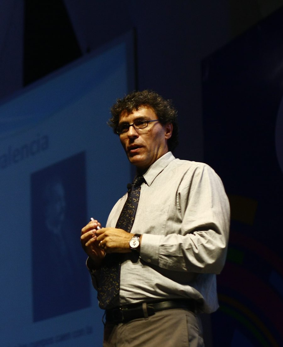 El físico mexicano Miguel Alcubierre dando una charla, con una diapositiva sobre el principio de equivalencia detrás