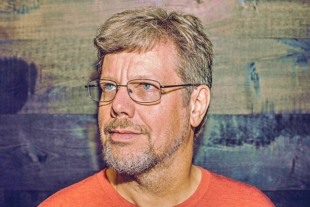 Retrato de Guido van Rossum con gafas y camiseta naranja