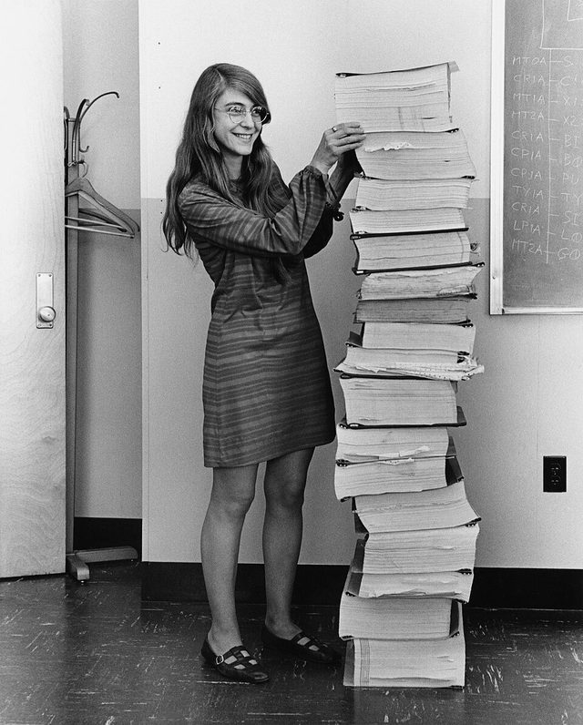 Margaret Hamilton en 1969, de pie junto a una pila de listados impresos del software de navegación del Apolo tan alta como ella